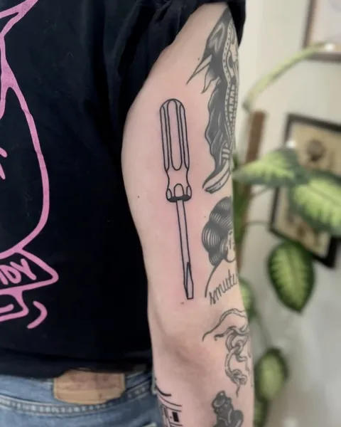 Ignorant tatuaż śrubokrętu na ramieniu z grubym konturem — Tattoo, Wujek Darek Tattoo, Warszawa