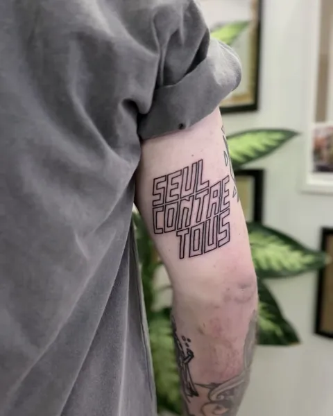 Ignorant tatuaż z trójliniowym liternictwem na zewnętrznej stronie ramienia — Tattoo, Wujek Darek Tattoo, Warszawa
