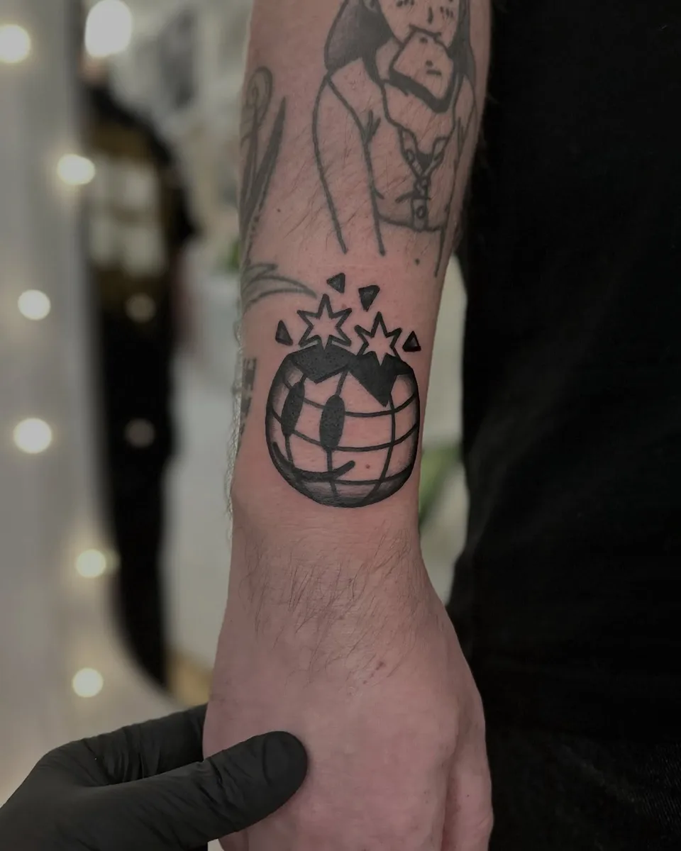 Ignorant tatuaż eksplodującego globusa na nadgarstku — Tattoo, Wujek Darek Tattoo, Warszawa