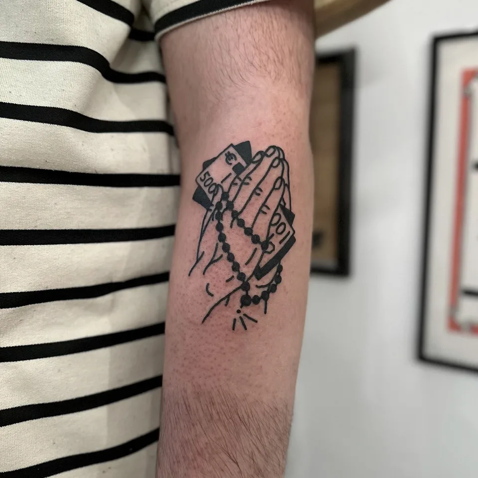 Tatuaż modlących się rąk z różańcem i banknotami w stylu ignorant — Tattoo, Wujek Darek Tattoo, Warszawa