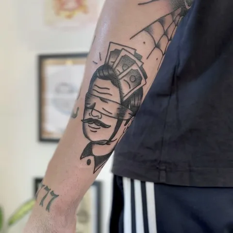 Ignorant tatuaż głowy mężczyzny z wąsem i banknotami na łokciu — Tattoo, Wujek Darek Tattoo, Warszawa