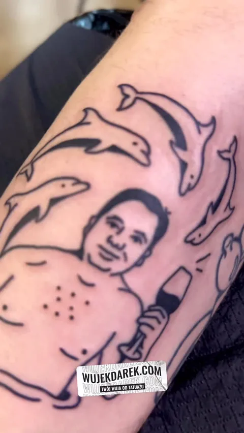 Ignorant tatuaż delfiny i postać mężczyzny na ramieniu — Tattoo, Wujek Darek Tattoo, Warszawa