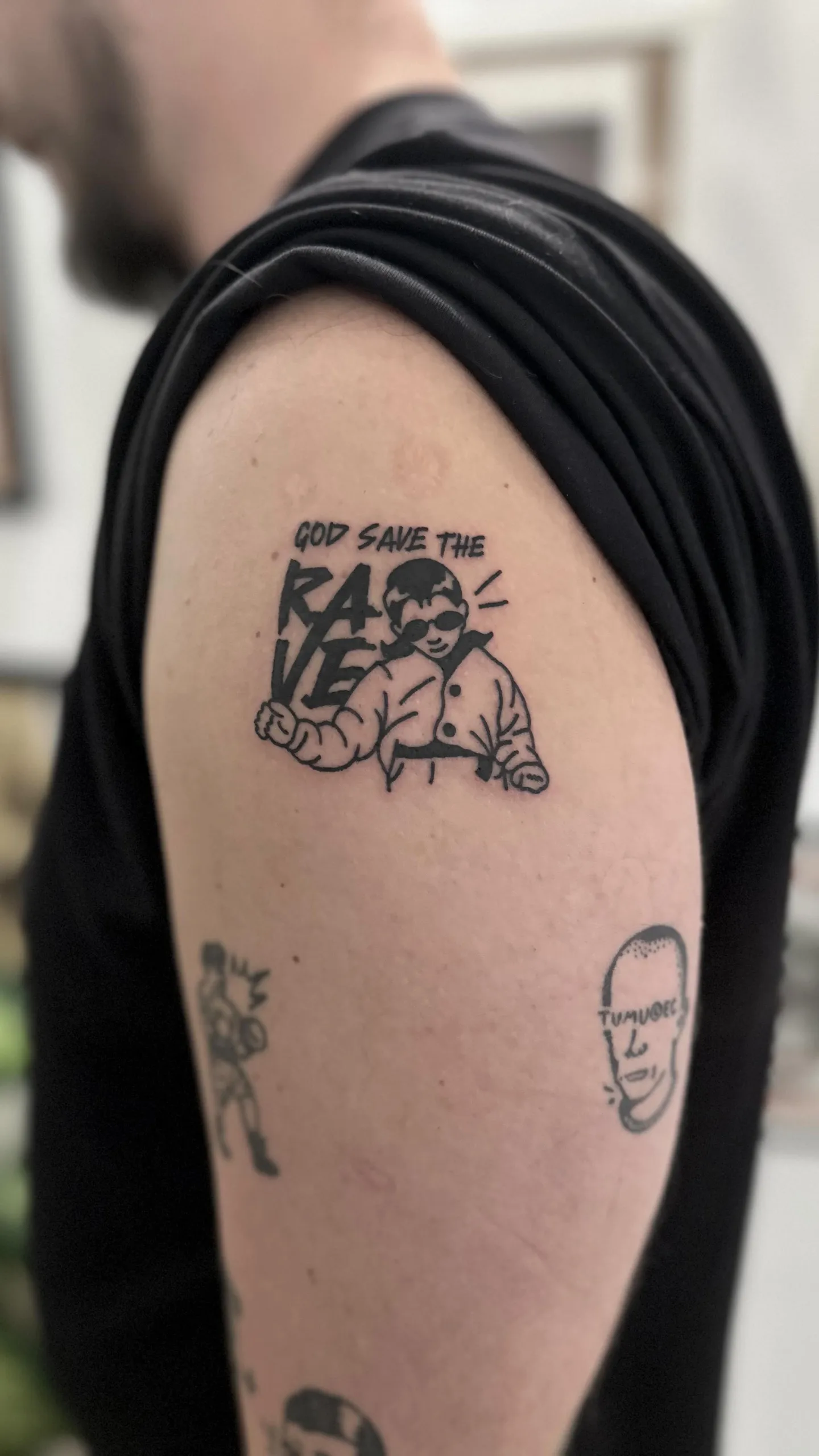 Ignorant tatuaż dziecka z okularami przeciwsłonecznymi na ramieniu — Tattoo, Wujek Darek Tattoo, Warszawa