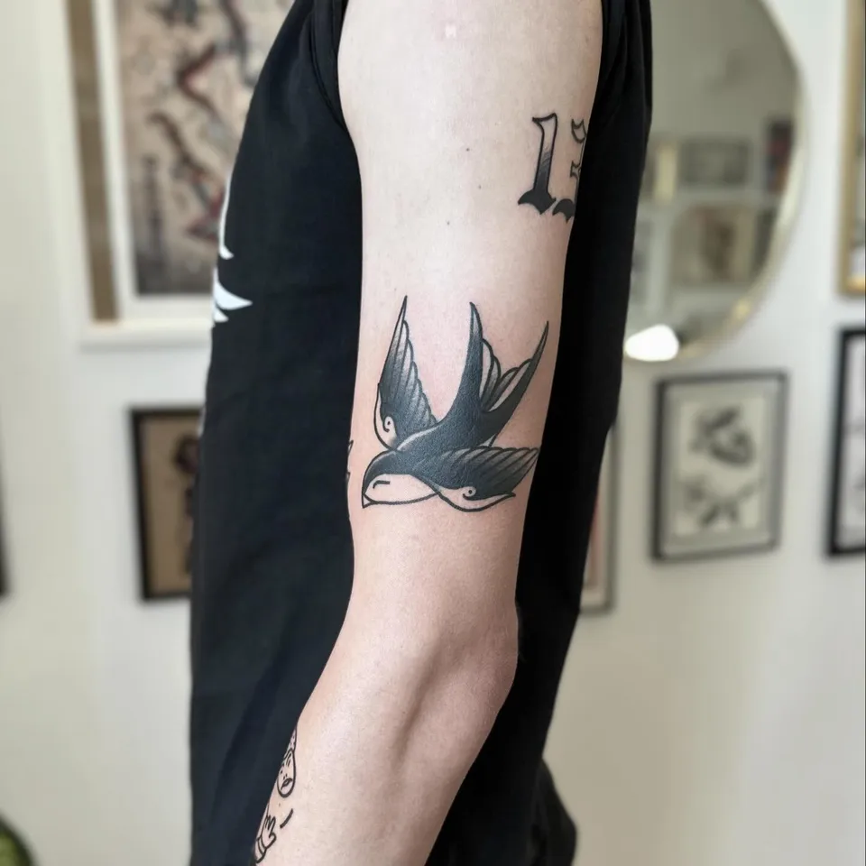 Tatuaż jaskółki w stylu gruby kontur na ramieniu — Tattoo, Wujek Darek Tattoo, Warszawa