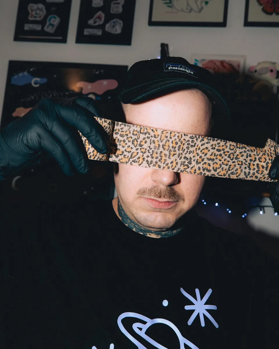 Artysta tatuażu w czarnych rękawiczkach z lamparcia opaską na oczach — Tattoo, Wujek Darek Tattoo, Warszawa