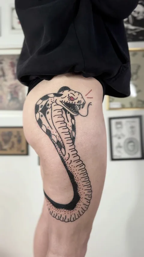 Ignorant tatuaż kobry na udzie z grubym konturem — Tattoo, Wujek Darek Tattoo, Warszawa