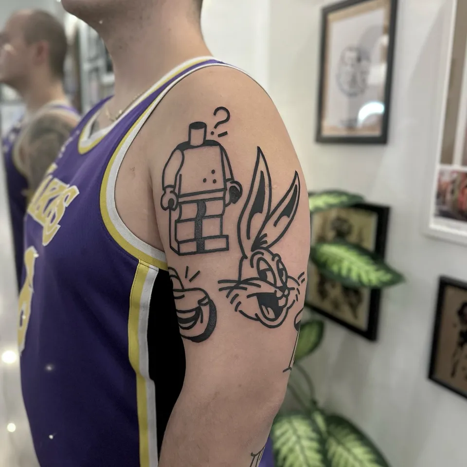 Ignorant tatuaż z figurką Lego i Królika Bugsa na ramieniu — Tattoo, Wujek Darek Tattoo, Warszawa