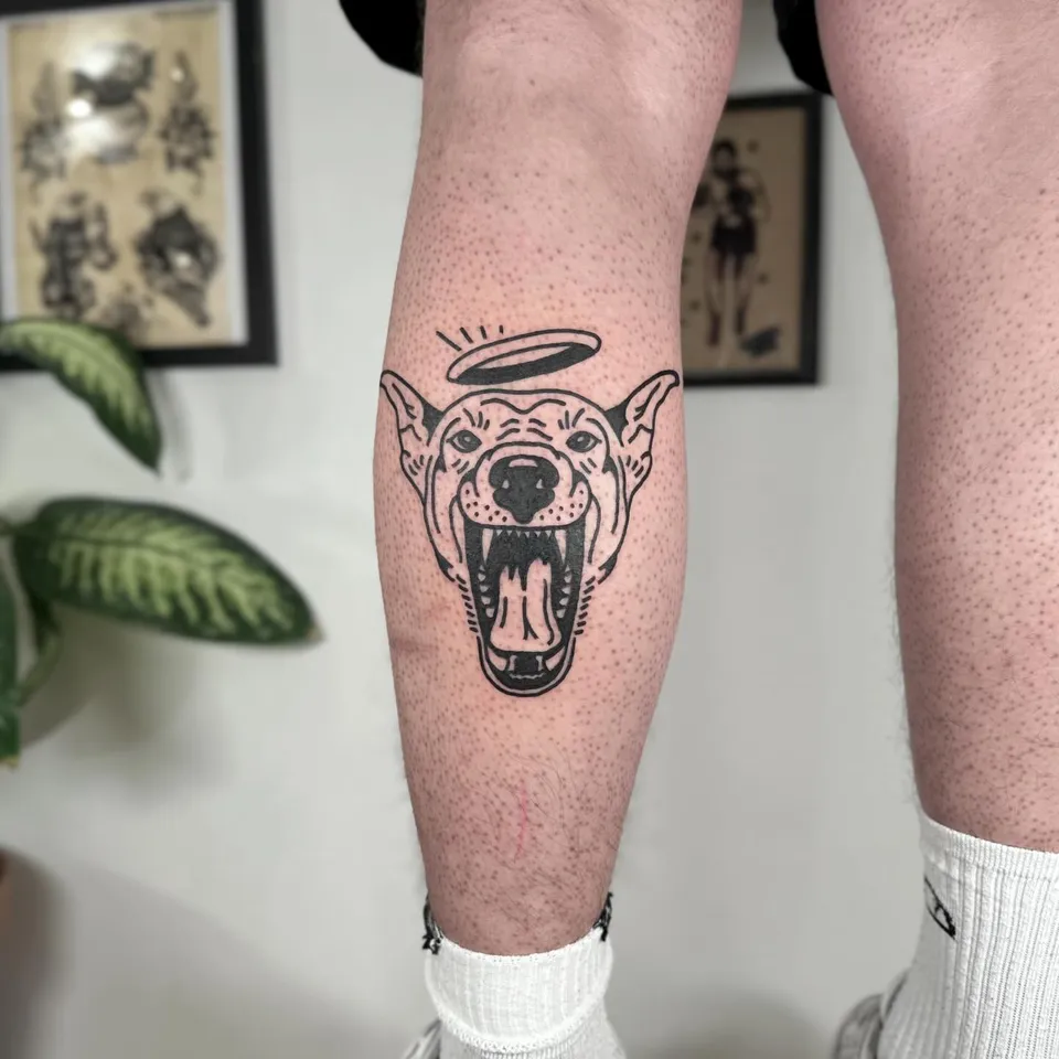 Ignorant tatuaż głowy psa z aureolą na łydce — Tattoo, Wujek Darek Tattoo, Warszawa
