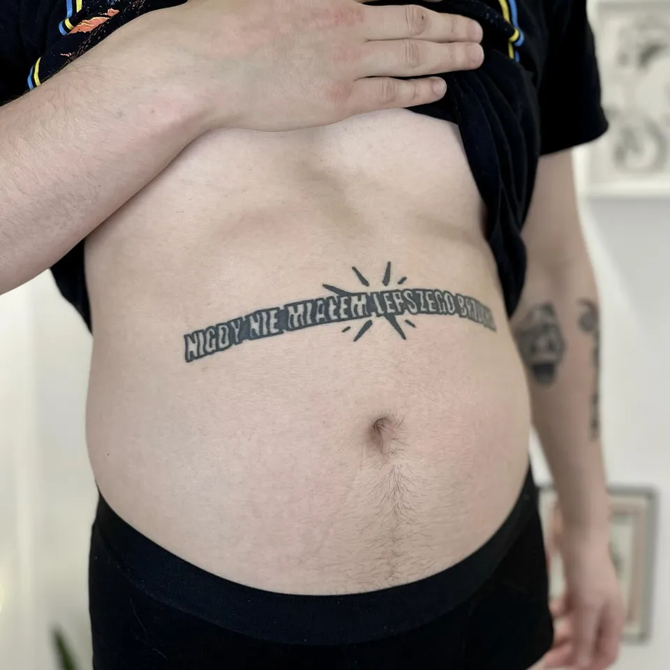Gruby kontur napis na brzuchu w stylu ignorant — Tattoo, Wujek Darek Tattoo, Warszawa