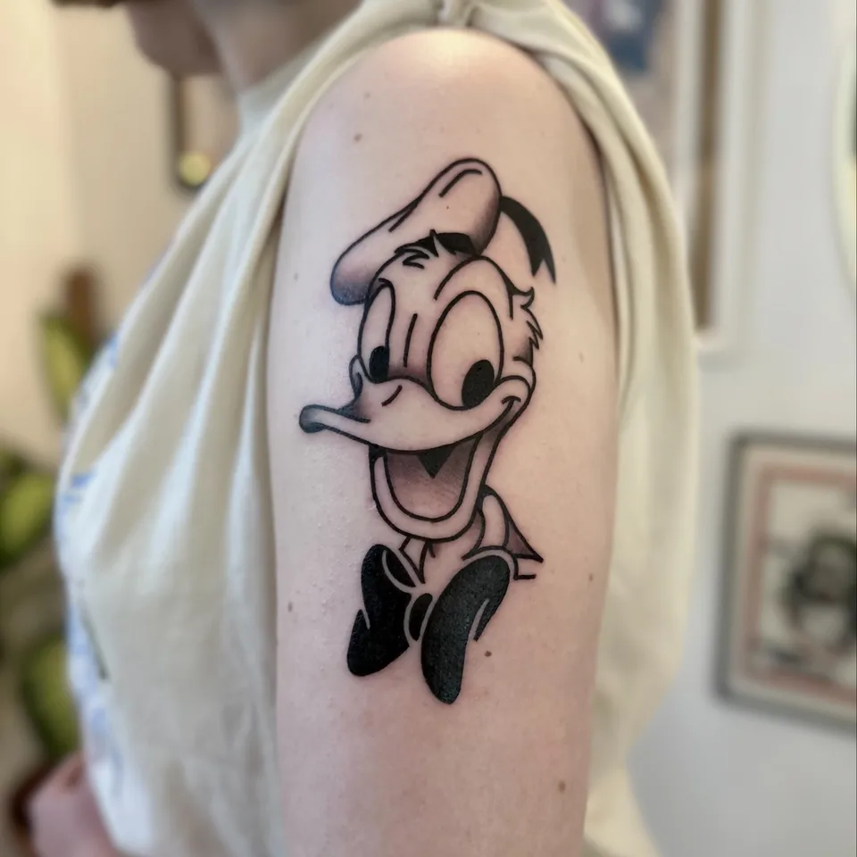 Gruby kontur tatuaż Donald Duck na ramieniu — Tattoo, Wujek Darek Tattoo, Warszawa