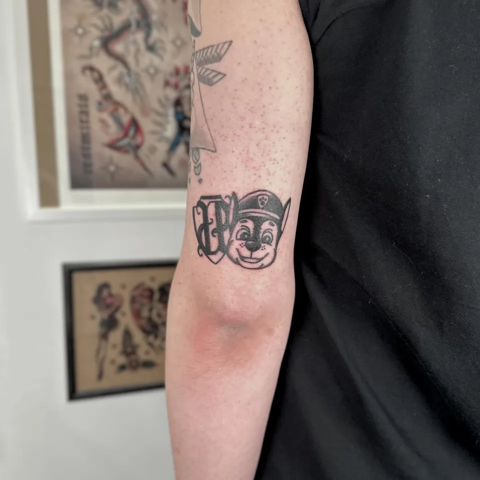 Ignorant tatuaż głowy psa w policyjnej czapce na przedramieniu (2) — Tattoo, Wujek Darek Tattoo, Warszawa