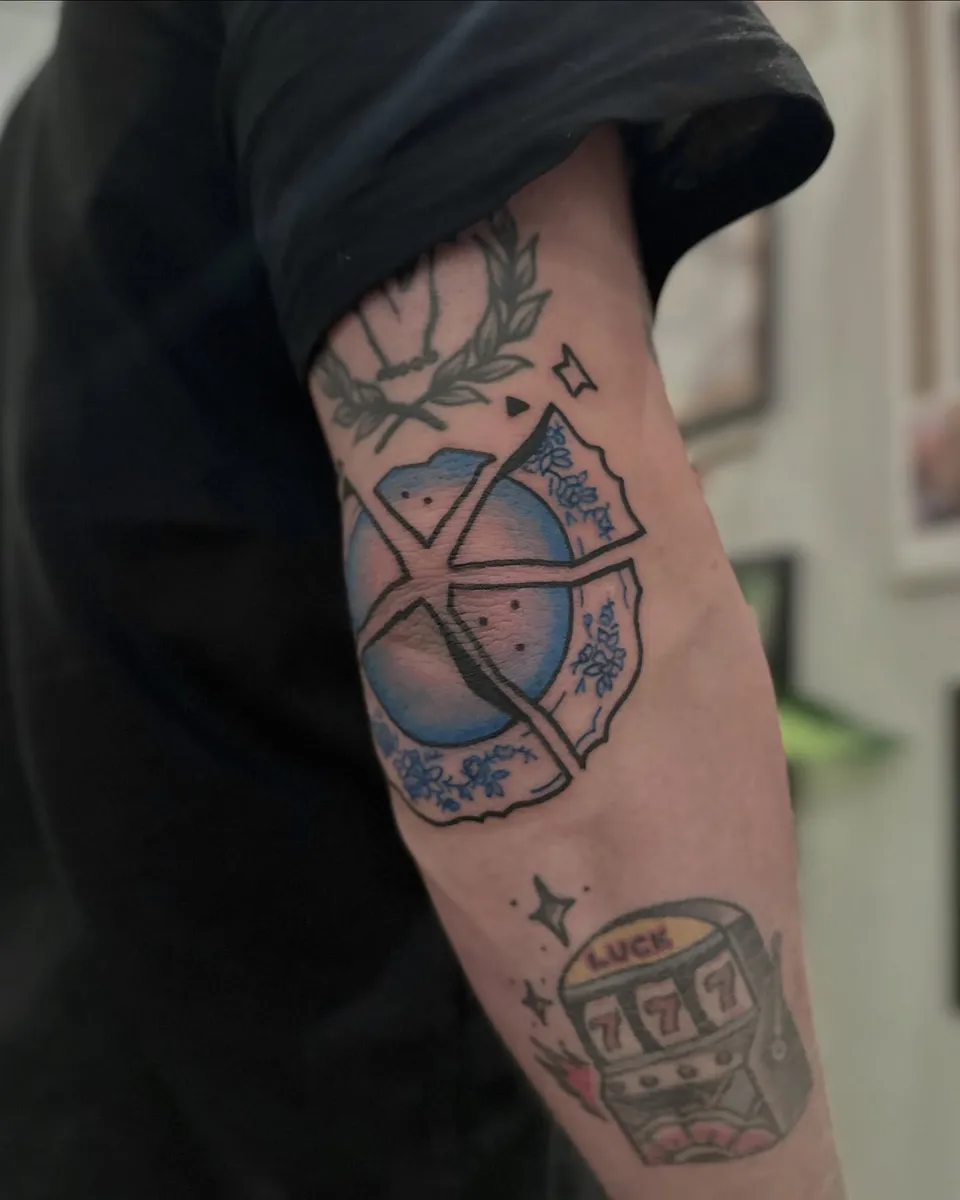 Ignorant tatuaż rozbitej porcelanowej kuli na łokciu z automatem do gry — Tattoo, Wujek Darek Tattoo, Warszawa