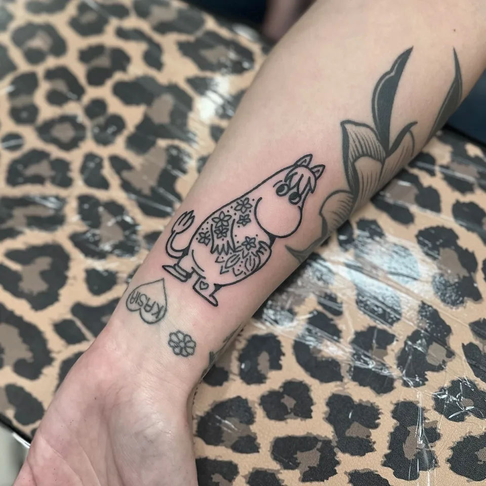 Tatuaż Muminku z motywami kwiatowymi na przedramieniu – gruby kontur — Tattoo, Wujek Darek Tattoo, Warszawa