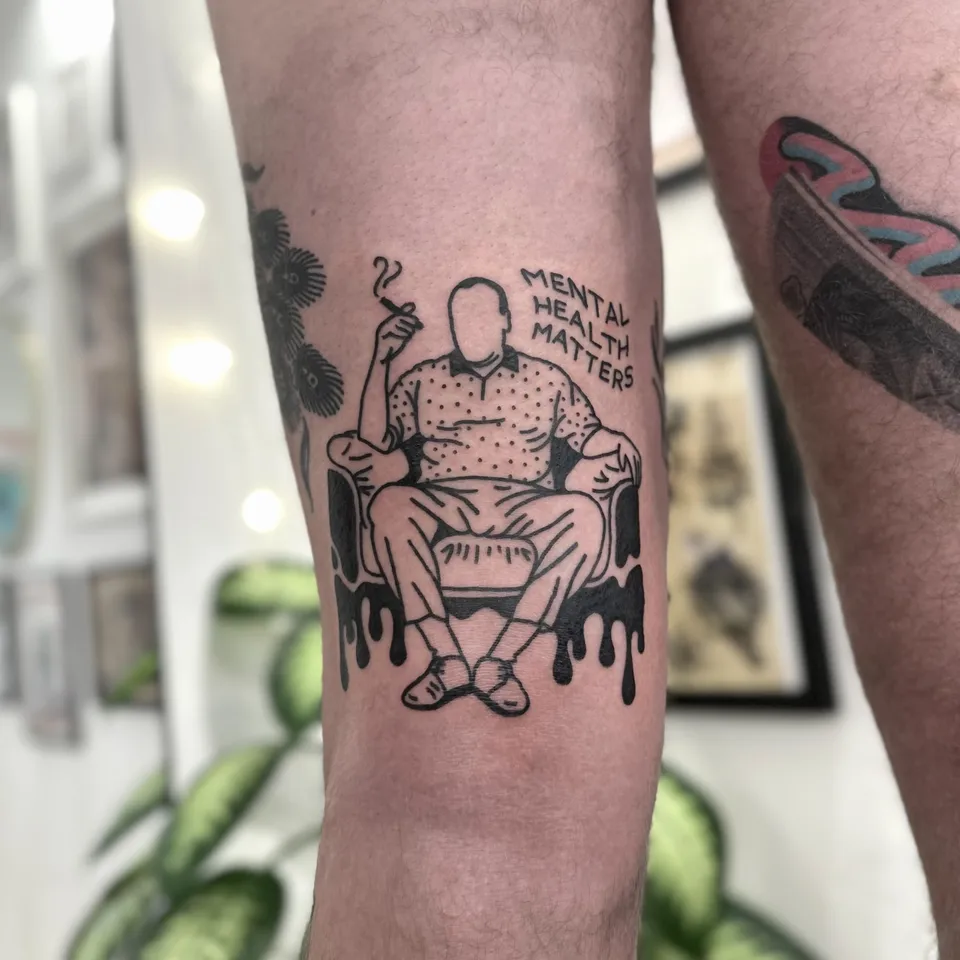 Ignorant tatuaż siedzącego mężczyzny na nodze z napisem w trzech liniach — Tattoo, Wujek Darek Tattoo, Warszawa
