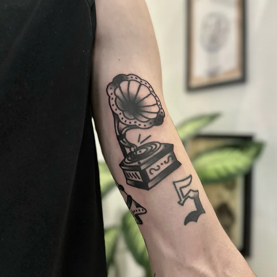 Tatuaż gramofonowy z nutami na przedramieniu w grubym konturze — Tattoo, Wujek Darek Tattoo, Warszawa