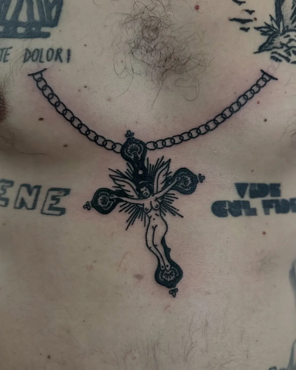 Tatuaż krzyża z nagą postacią na łańcuchu na klatce piersiowej — Tattoo, Wujek Darek Tattoo, Warszawa