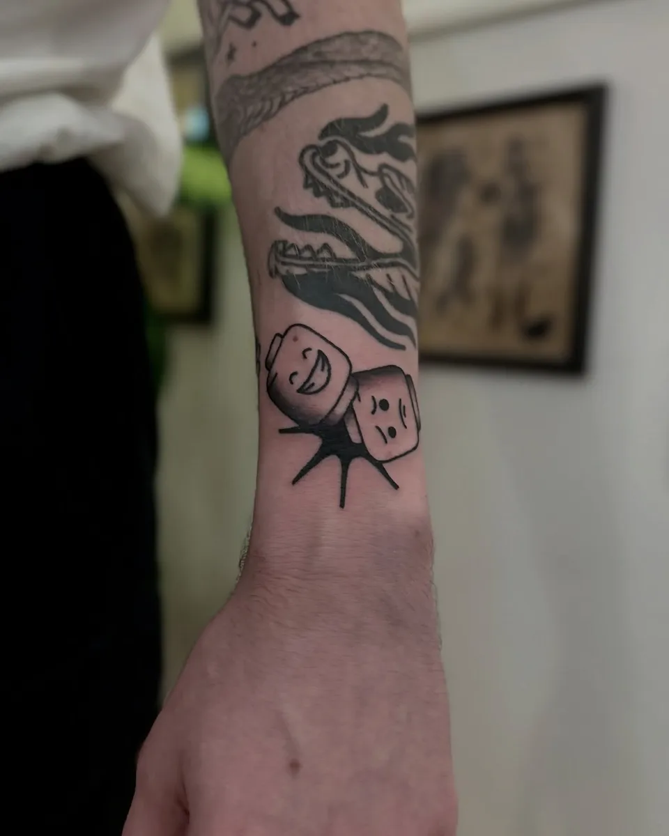 Ignorant tatuaż dwóch kostek do gry z twarzami na nadgarstku (2) — Tattoo, Wujek Darek Tattoo, Warszawa