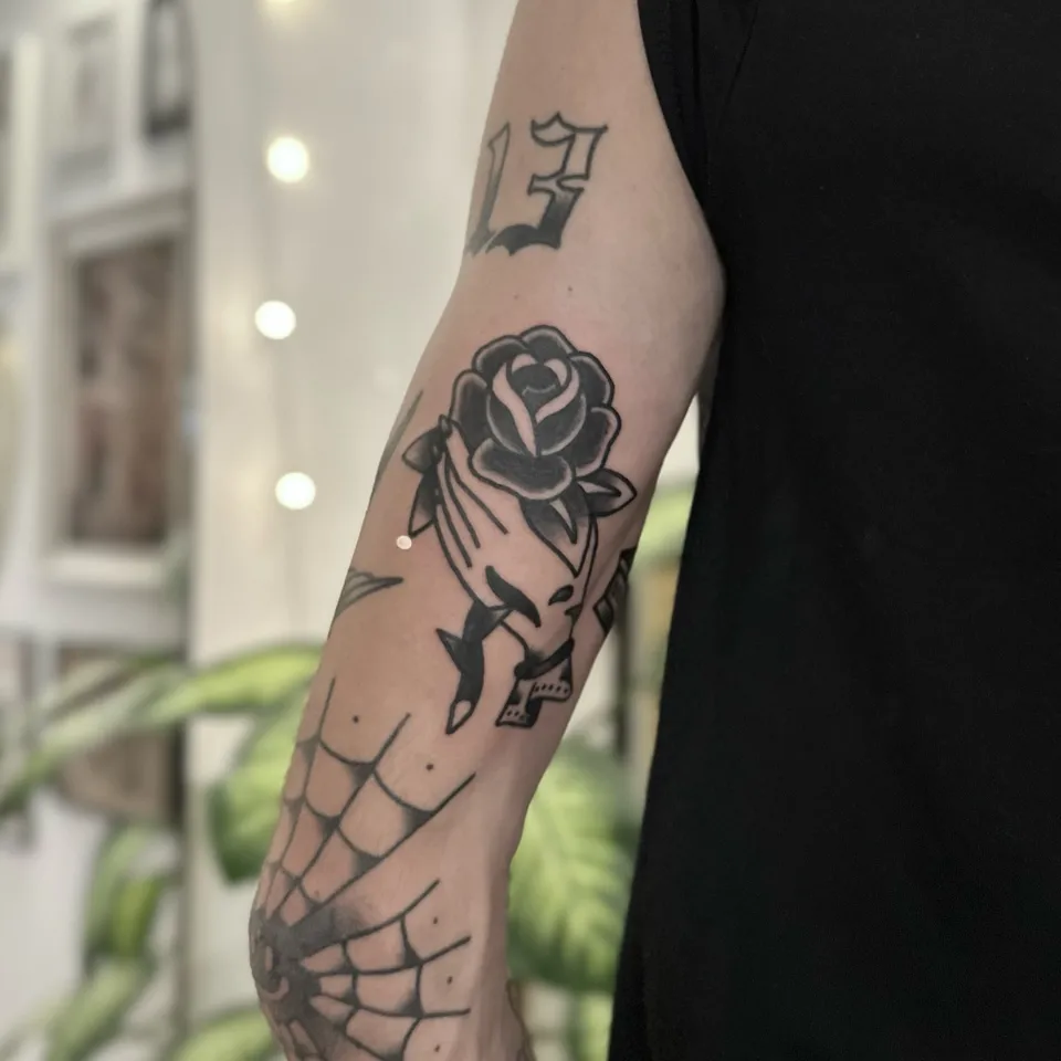 Gruby kontur – róża trzymana przez dłoń szkieletu na przedramieniu — Tattoo, Wujek Darek Tattoo, Warszawa