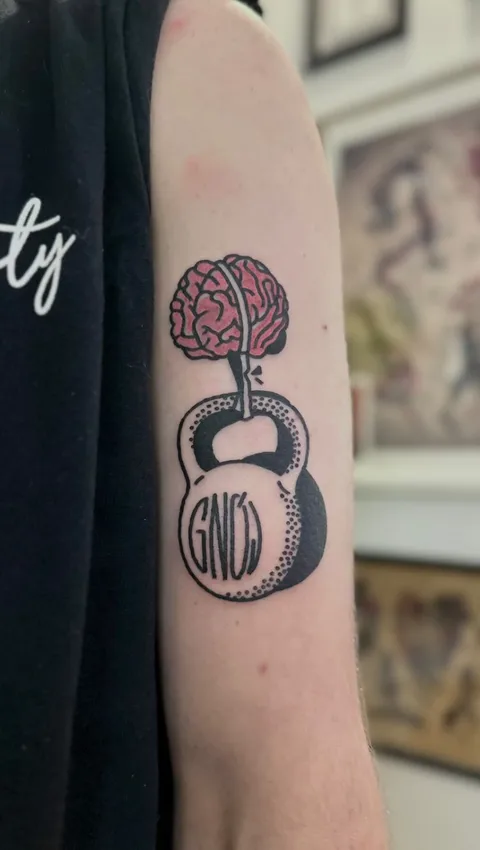 Tatuaż mózgu i kettlebella z grubym konturem na przedramieniu — Tattoo, Wujek Darek Tattoo, Warszawa