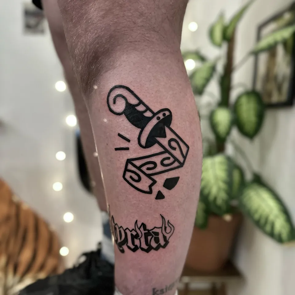Ignorant tatuaż sztylet wbity w kostkę do gry na łydce — Tattoo, Wujek Darek Tattoo, Warszawa