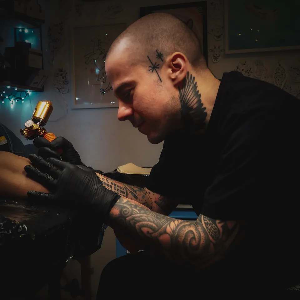 Tatuator z tatuażami na twarzy i szyi podczas pracy maszyną rotacyjną — Tattoo, Wujek Darek Tattoo, Warszawa