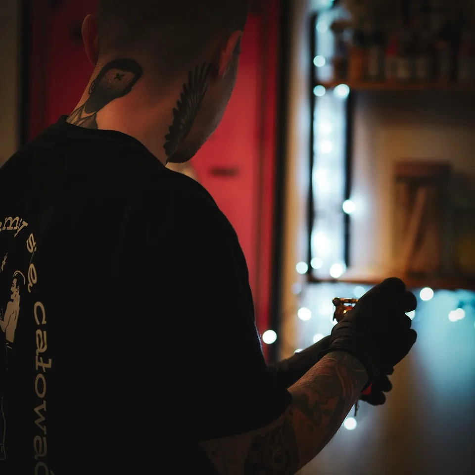Tatuator z tatuażami na twarzy i szyi podczas pracy maszyną rotacyjną (5) — Tattoo, Wujek Darek Tattoo, Warszawa
