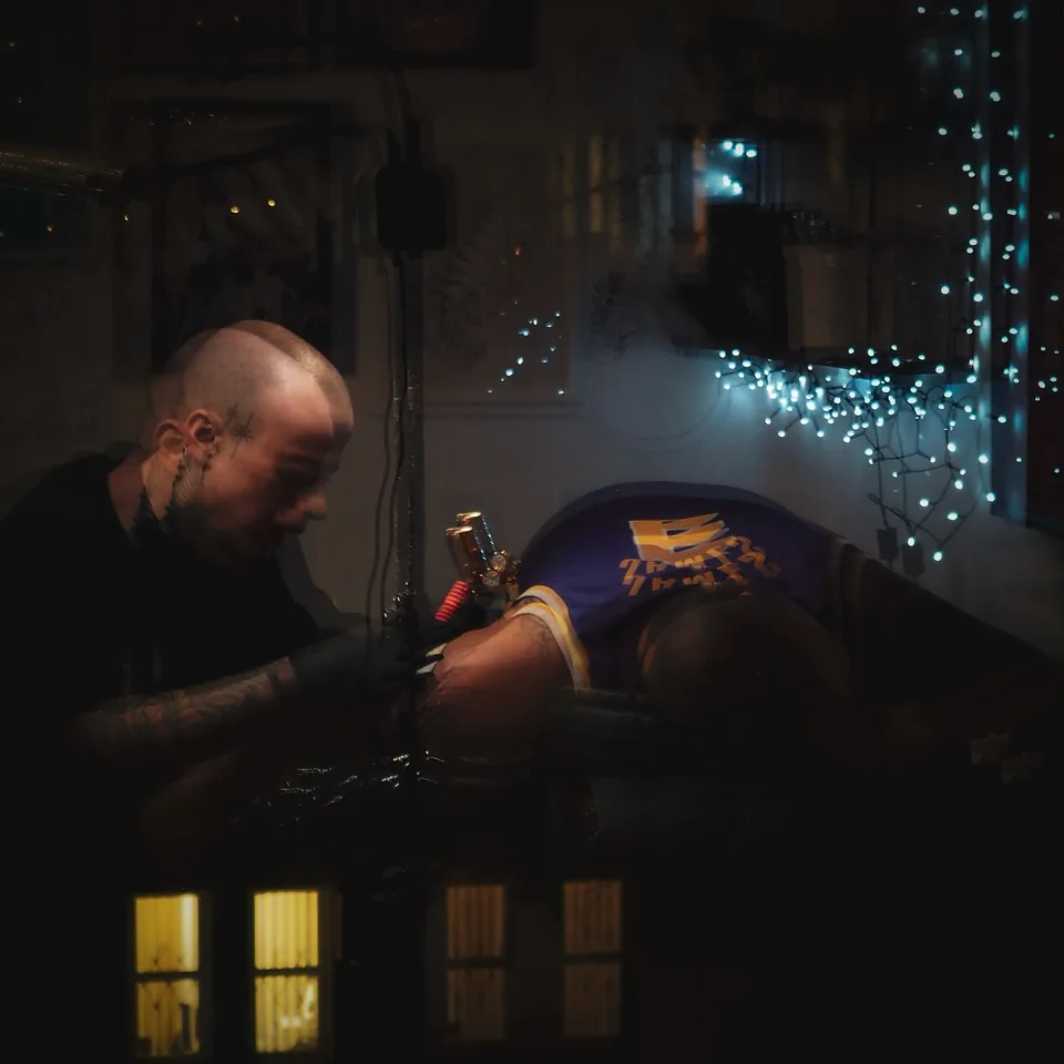 Tatuator z tatuażami na twarzy i szyi podczas pracy maszyną rotacyjną (7) — Tattoo, Wujek Darek Tattoo, Warszawa