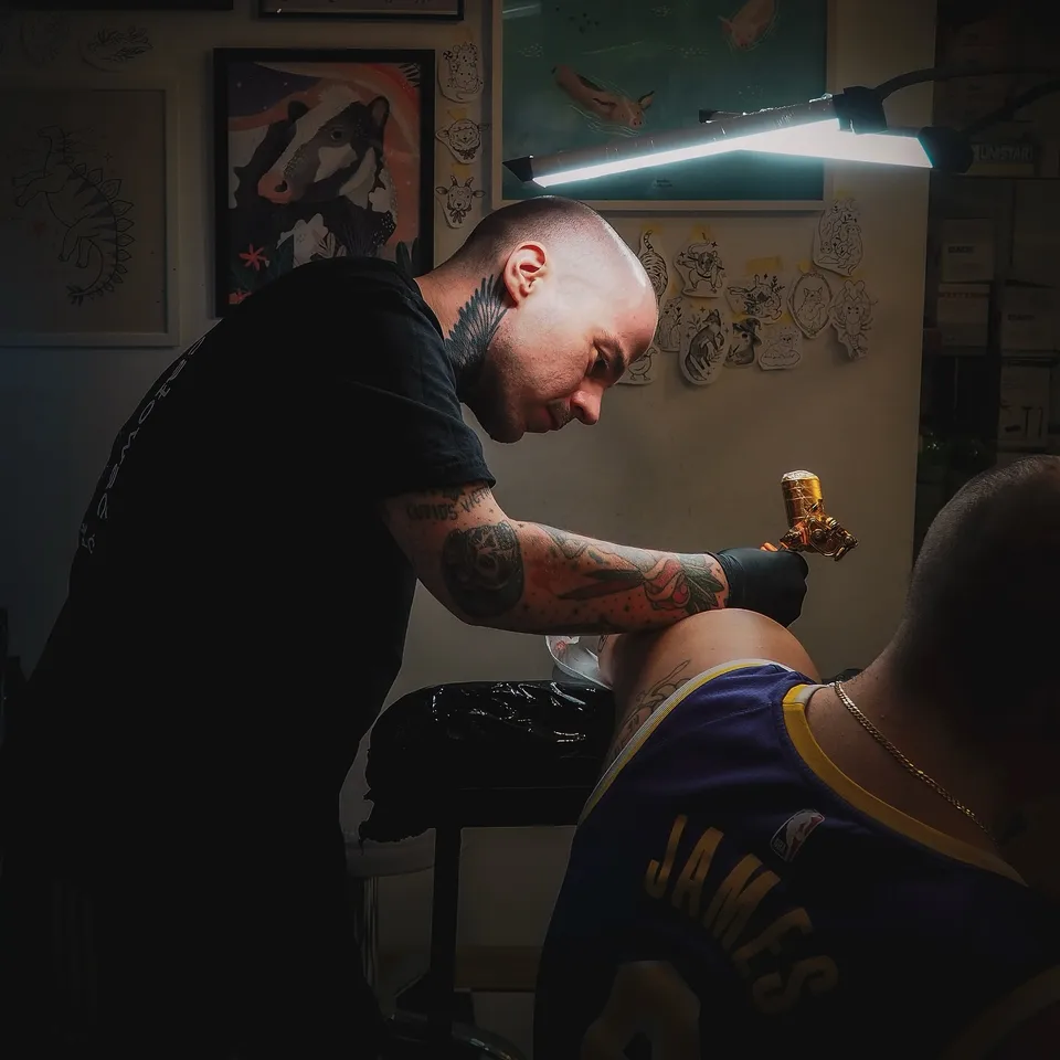 Tatuator z tatuażami na twarzy i szyi podczas pracy maszyną rotacyjną (8) — Tattoo, Wujek Darek Tattoo, Warszawa