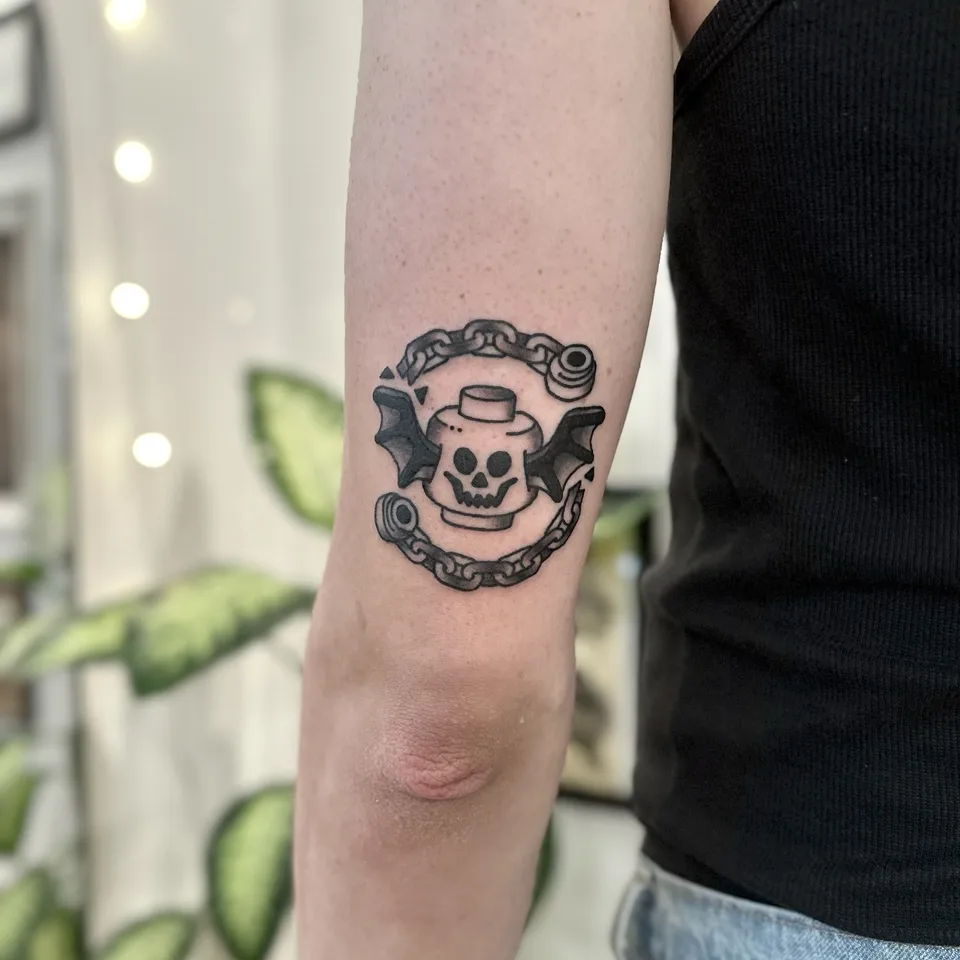 Gruby kontur tatuaż czaszki LEGO z nietoperzymi skrzydłami i łańcuchem (2) — Tattoo, Wujek Darek Tattoo, Warszawa