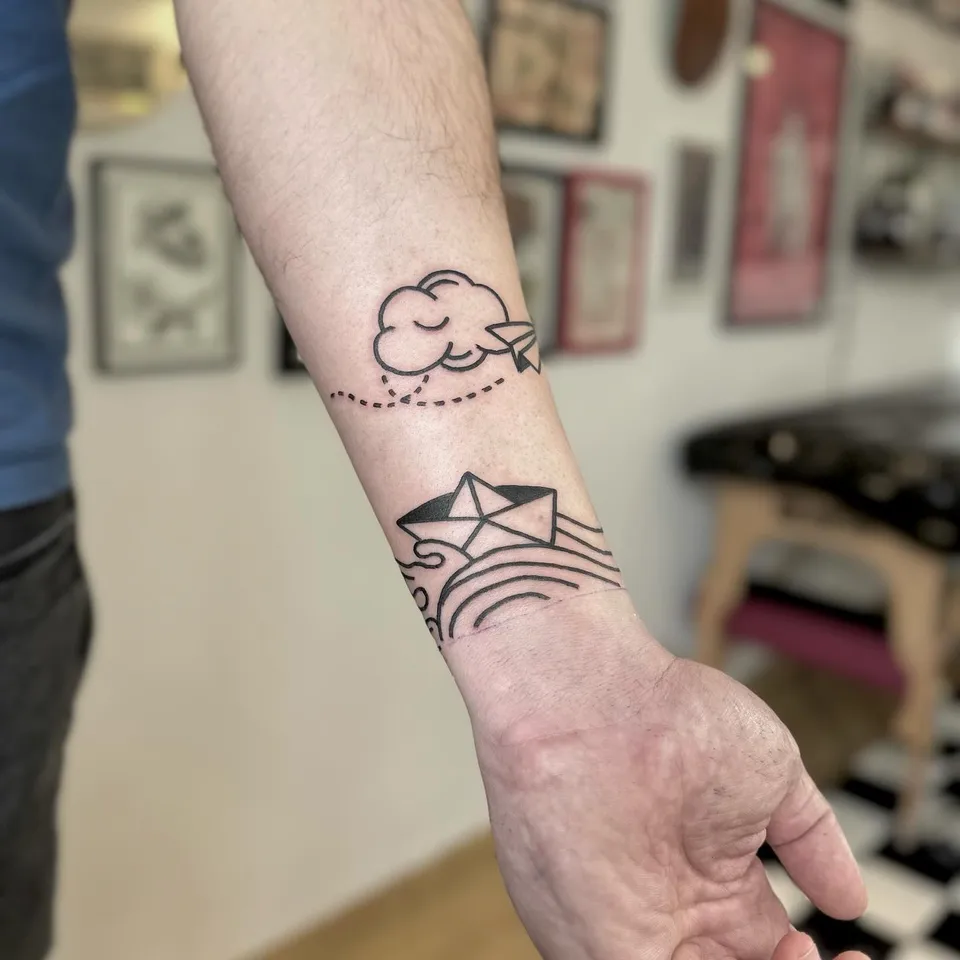Tatuaż papierowego samolotu z chmurą i papierowej łódki na fali — Tattoo, Wujek Darek Tattoo, Warszawa