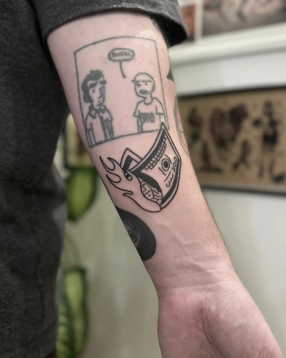 Ignorant tatuaż komiksowy z postaciami i rolką banknotów w płomieniach na przedramieniu (2) — Tattoo, Wujek Darek Tattoo, Warszawa