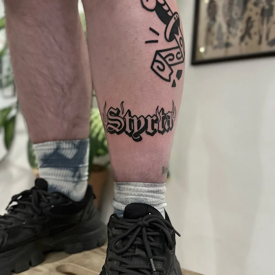 Tatuaż z grubym konturem – słowo w stylu gotyckim z motywem płomieni na łydce (3) — Tattoo, Wujek Darek Tattoo, Warszawa