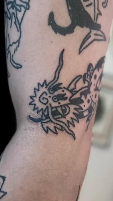 Ignorant tatuaż głowy smoka na łokciu z grubym konturem — Tattoo, Wujek Darek Tattoo, Warszawa