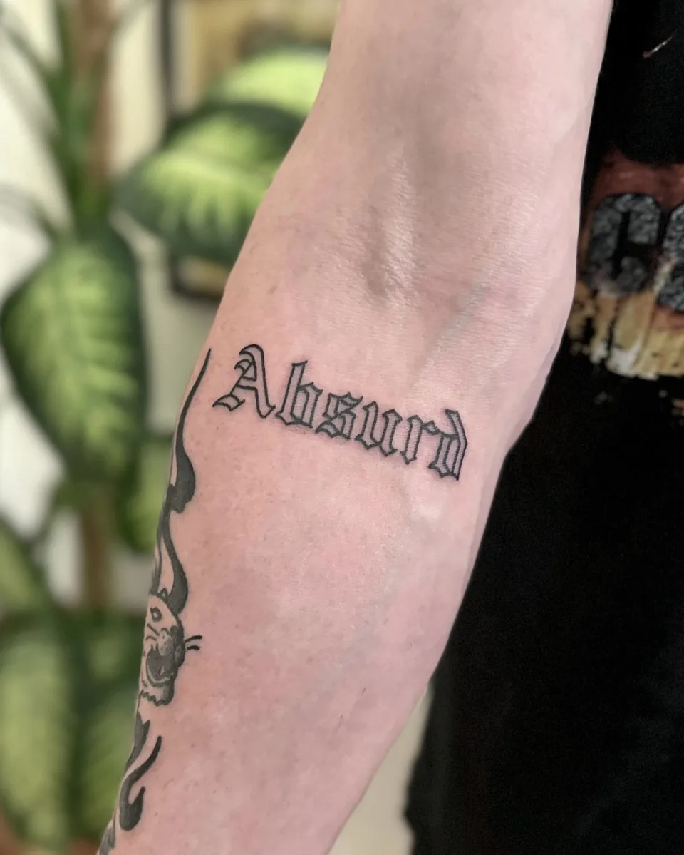 Ignorant tatuaż z jednym słowem w gotyckim kroju na przedramieniu — Tattoo, Wujek Darek Tattoo, Warszawa