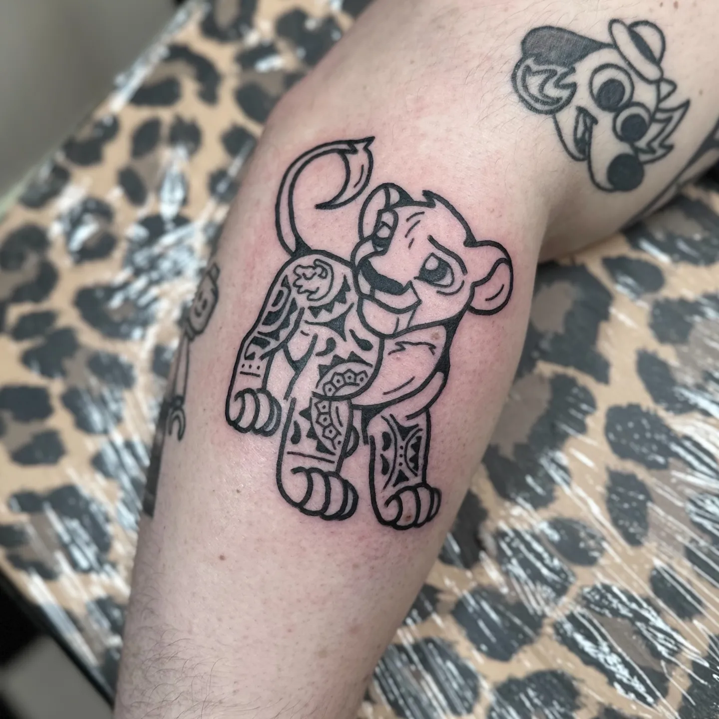 Gruby kontur tatuaż lwiątka Simby z wzorami mandali na nodze — Tattoo, Wujek Darek Tattoo, Warszawa
