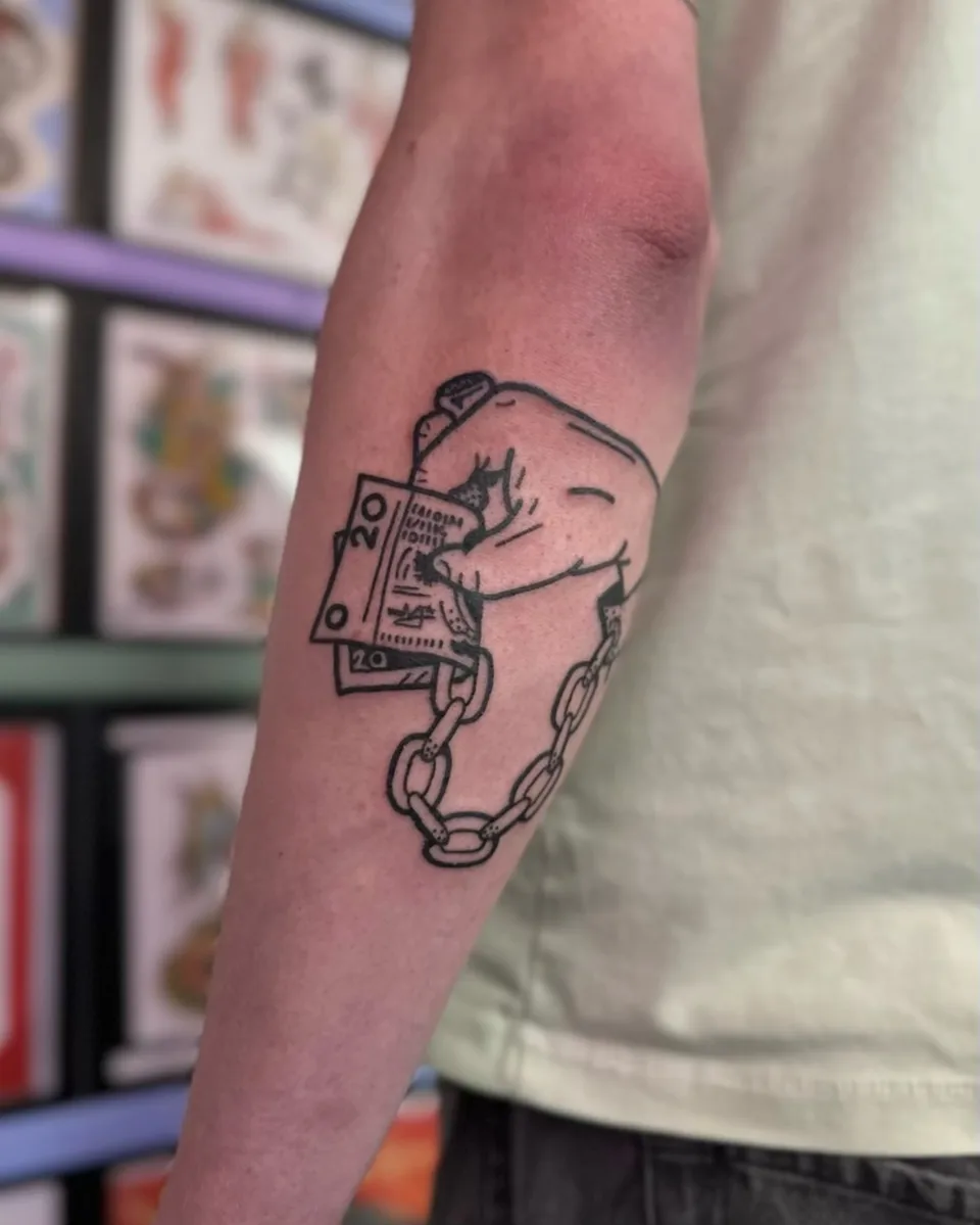 Ignorant tatuaż zaciśniętej pięści z banknotami i łańcuchem na przedramieniu — Tattoo, Wujek Darek Tattoo, Warszawa
