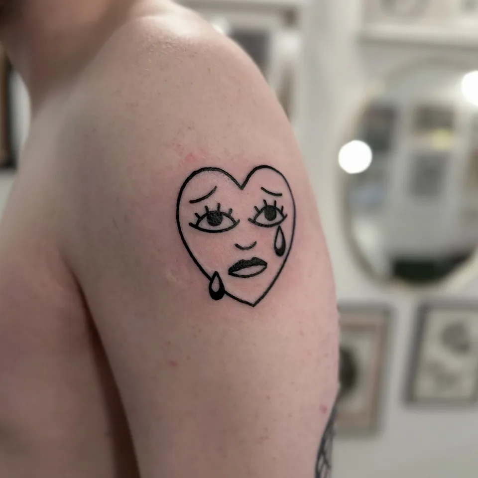Ignorant tatuaż płaczącego serca z twarzą na ramieniu — Tattoo, Wujek Darek Tattoo, Warszawa