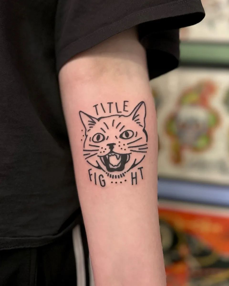 Ignorant tatuaż kociej głowy z napisem na przedramieniu — Tattoo, Wujek Darek Tattoo, Warszawa