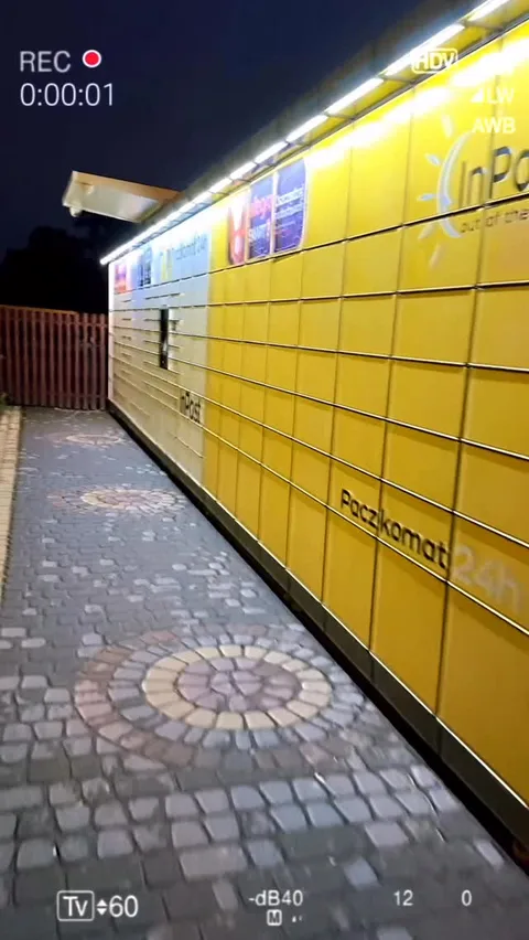Paczkomat nocą — żółta skrytka na tle brukowanego chodnika — Tattoo, Wujek Darek Tattoo, Warszawa
