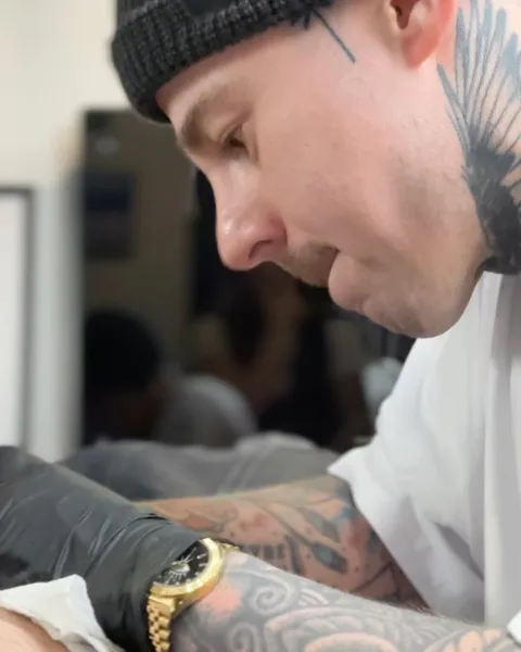 Tatuażysta z tatuażami na twarzy i szyi podczas pracy w studio — Tattoo, Wujek Darek Tattoo, Warszawa
