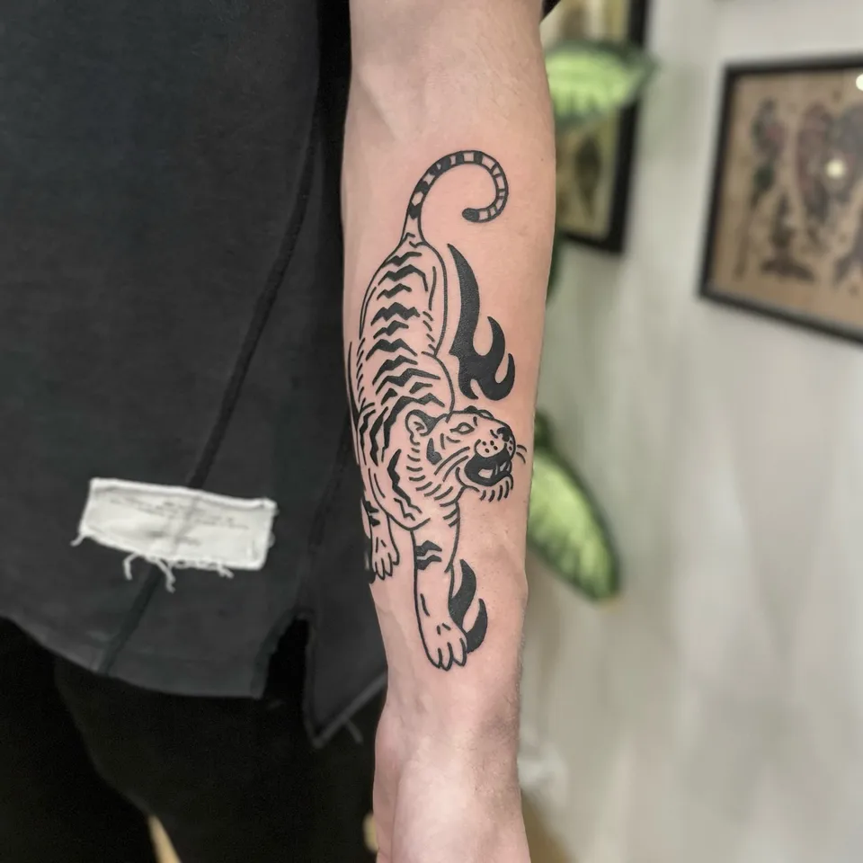 Gruby kontur tatygrys na przedramieniu z płomieniami w stylu ignorant — Tattoo, Wujek Darek Tattoo, Warszawa