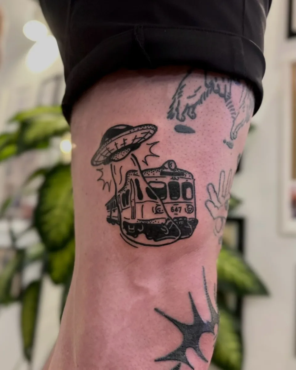 Ignorant tatuaż UFO porywającego tramwaj na nodze — Tattoo, Wujek Darek Tattoo, Warszawa