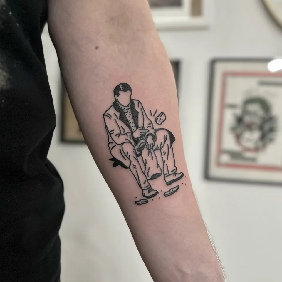 Ignorant tatuaż siedzącego mężczyzny w garniturze na przedramieniu — Tattoo, Wujek Darek Tattoo, Warszawa