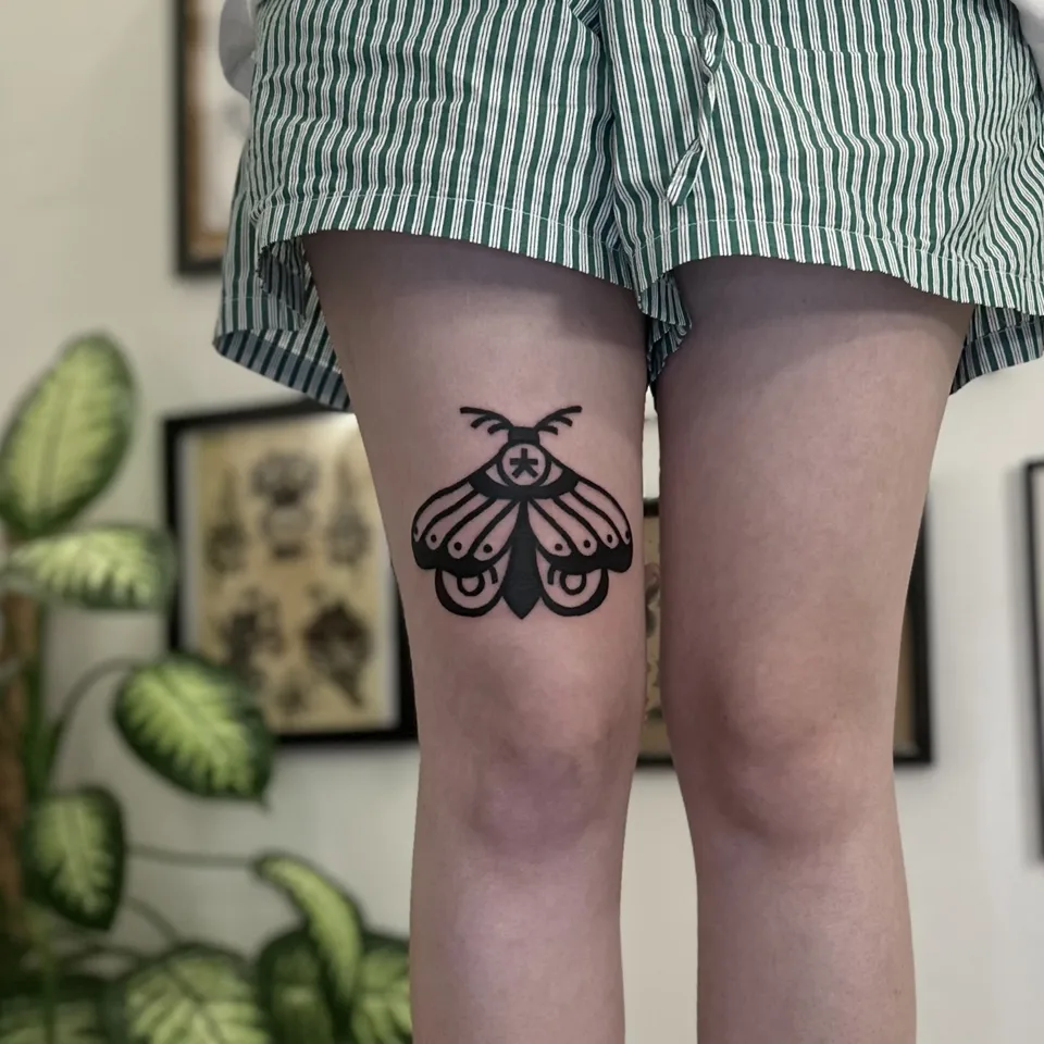 Gruby kontur tatuaż ćmy z okiem na udzie — Tattoo, Wujek Darek Tattoo, Warszawa
