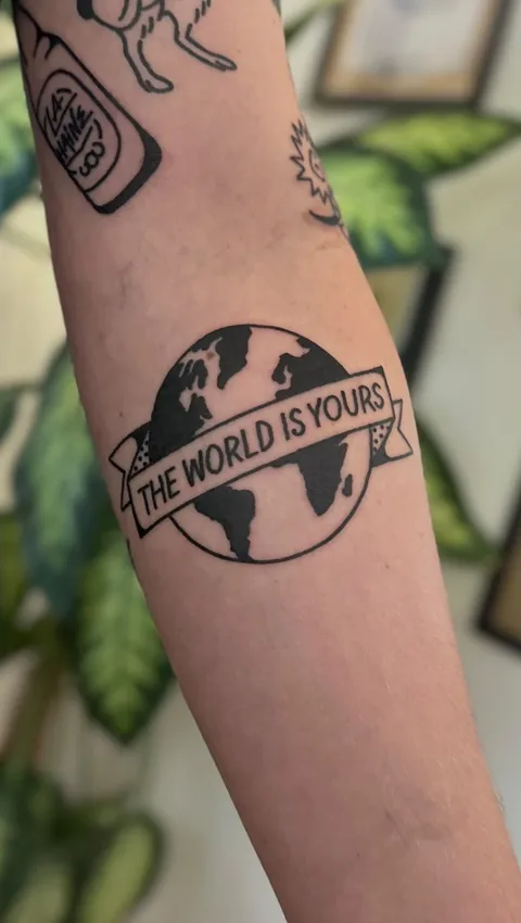Tatuaż globu z banerowym napisem na przedramieniu w stylu gruby kontur — Tattoo, Wujek Darek Tattoo, Warszawa