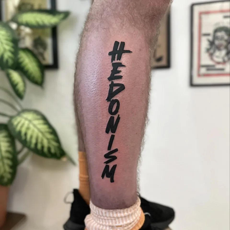 Ignorant tatuaż z pionowym napisem na łydce – gruby kontur (2) — Tattoo, Wujek Darek Tattoo, Warszawa